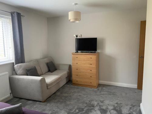 a living room with a couch and a tv on a wooden dresser at Luxury Bungalow Countryside view in Aughton