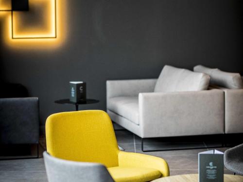 a living room with a yellow chair and a couch at ibis Wels in Wels