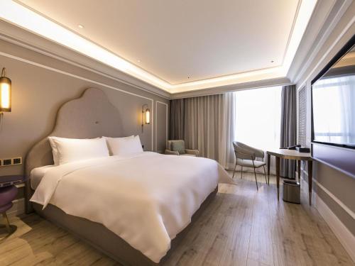 a hotel room with a large bed and a television at Mercure Ordos Downtown in Ordos