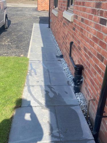 a sidewalk next to a brick building with a fire hydrant at Luxury Bungalow Countryside view in Aughton