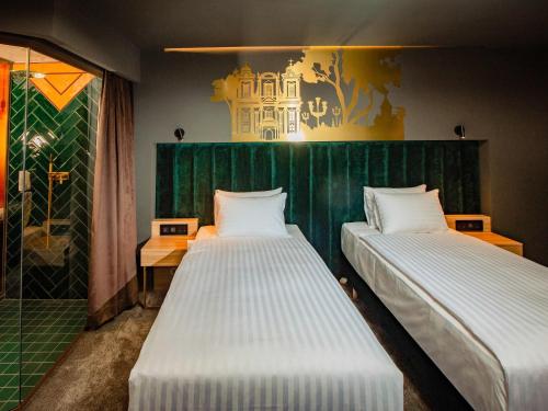 two beds in a room with a green wall at Mercure Timisoara in Timişoara
