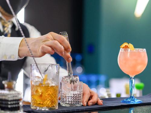 a person is preparing two cocktails on a bar at Mercure Timisoara in Timişoara