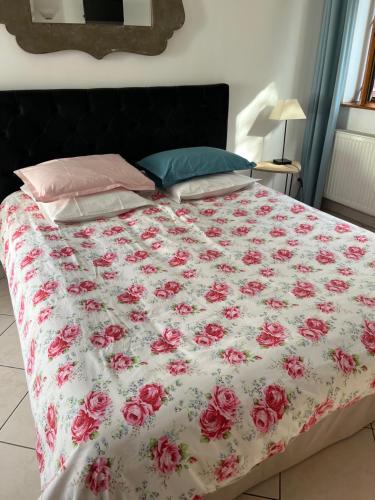 a bed with a floral comforter on it at La Ferme de la Place in Bouvines