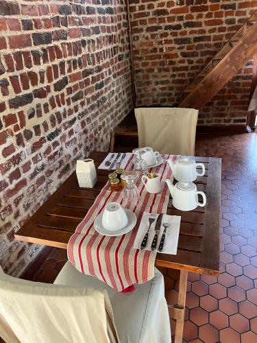 a wooden table with plates and cups on it at La Ferme de la Place in Bouvines