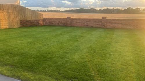 a yard with a brick wall and green grass at Luxury Bungalow Countryside view in Aughton