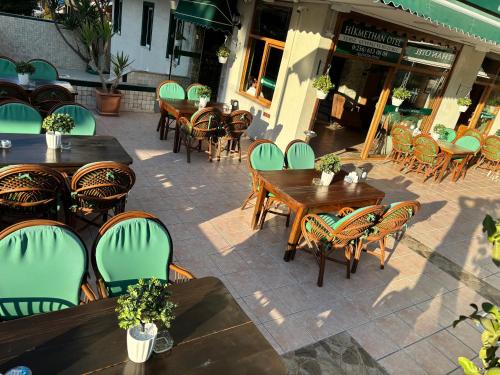 an outdoor patio with wooden tables and chairs at Hikmethan Otel in Kusadası