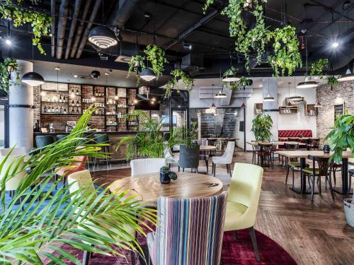 a restaurant with tables and chairs and plants at ibis Styles Lublin Stare Miasto in Lublin