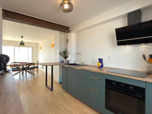 Sea view duplex في فالراس بلاج: مطبخ بخزائن زرقاء وطاولة خشبية