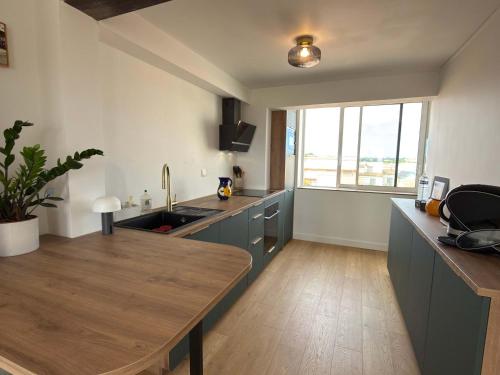 Sea view duplex في فالراس بلاج: مطبخ بخزائن زرقاء وطاولة خشبية