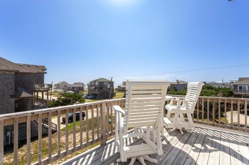 two chairs and a table on a deck with the ocean at 8076 - Siren's Serenade in Rodanthe