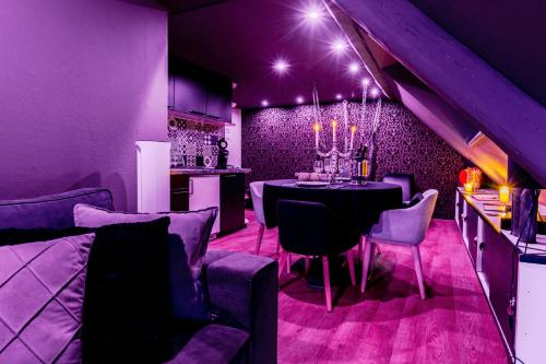 a dining room with a table and purple lighting at Love Room Alsace Escale du Désir in Niederbronn-les-Bains