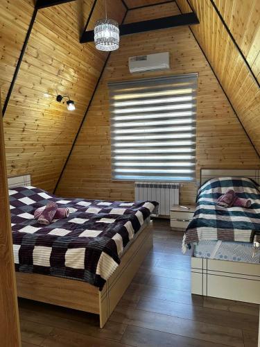 a attic bedroom with two beds and a window at A-Frame Armudlu in Gabala