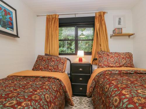 two beds in a room with a window at Moon Cottage in Troutbeck Bridge