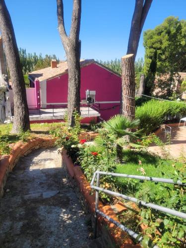 a garden in front of a pink house with trees at Villa Pachita in Alhama de Aragón