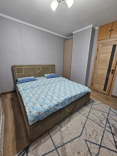 Un dormitorio con una cama con un edredón azul. en Lumi, en Bishkek