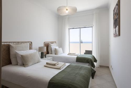 a bedroom with two beds and a large window at Golfinho - Sea view with pool by HD in Quarteira