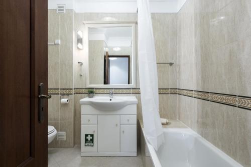 a bathroom with a sink and a toilet and a mirror at Golfinho - Sea view with pool by HD in Quarteira