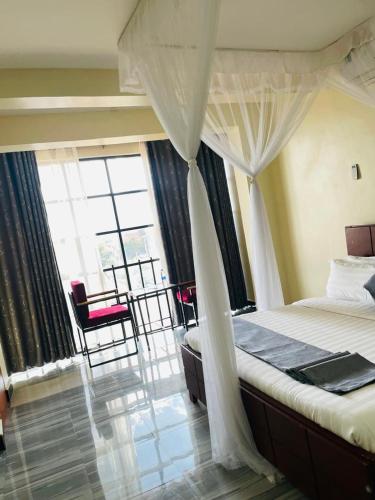 a bedroom with a bed and a large window at Kamwe kamwe hotel and spaa in Kasese