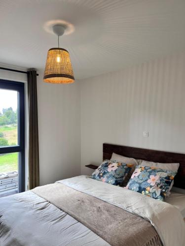 a bedroom with a bed with a lamp and a window at Au pré de la fauchée in Bièvre