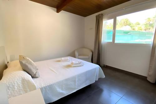 ein Schlafzimmer mit einem weißen Bett und einem Fenster in der Unterkunft Finca House By Fataga Maspalomas in Artedara