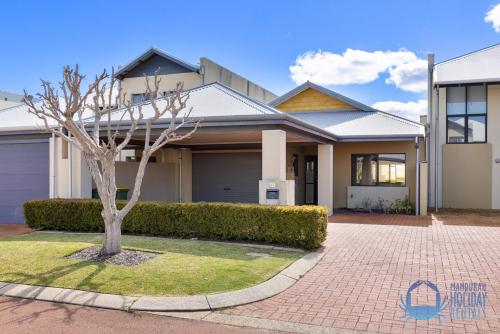 a house with a tree in front of it at Lazy Jetty Days Halls Head in Mandurah