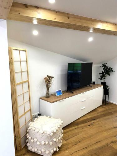 a living room with a tv on a white cabinet at Cozy Alpenloft Chiemsee by Dollop Living in Bernau am Chiemsee