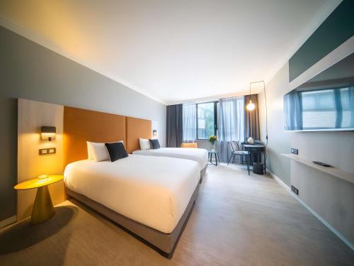 a hotel room with two beds and a desk at Maek Hotel Antwerp Central - Handwritten Collection in Antwerp
