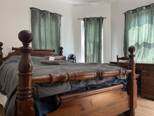 1 dormitorio con cama de madera y cortinas verdes en Relaxing, Calming PR by Binghamton University, en Johnson City