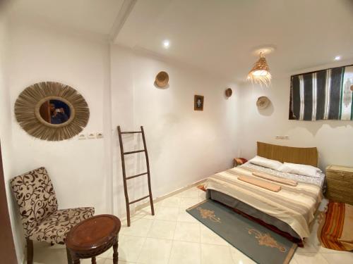 a bedroom with a bed and a ladder and a chair at Bright Wave Surfhouse in Tamraght Ouzdar