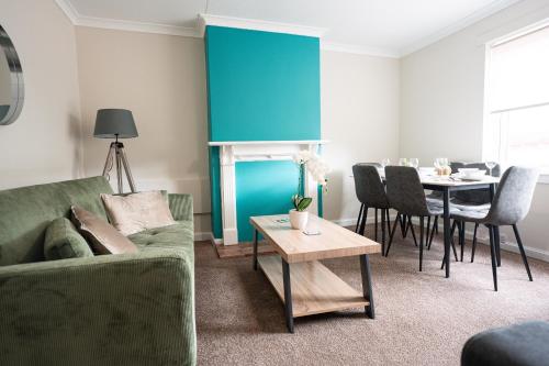 a living room with a green couch and a table at 3 BDR House At Caledonia Luxe Stays Short Lets & Serviced Accommodation Falkirk in Polmont