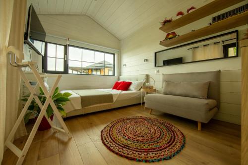 a bedroom with a bed and a couch and a chair at 1001 Village in Jugureni