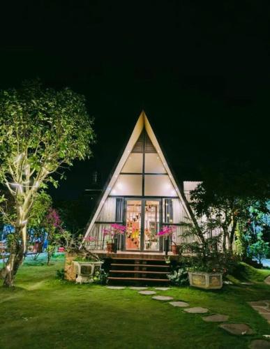 a small house with a pointed roof in a yard at Mộc Hoa Viên Homestay in Ấp Thiện Lập