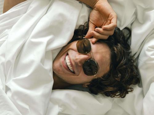 a man laying in bed with sunglasses on his face at Novotel Paris Porte Versailles in Paris