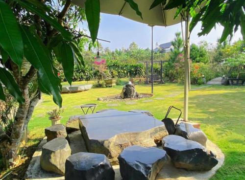 a garden with a table and rocks and an umbrella at Mộc Hoa Viên Homestay in Ấp Thiện Lập