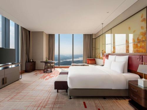 a hotel room with a large bed and a television at Pullman Huizhou Kaisa in Huizhou