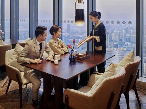 three people sitting at a table in a restaurant at Pullman Huizhou Kaisa in Huizhou