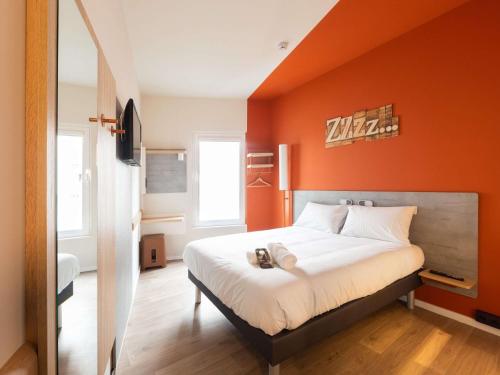 a bedroom with an orange wall with a bed at Ibis Budget Bilbao City in Bilbao