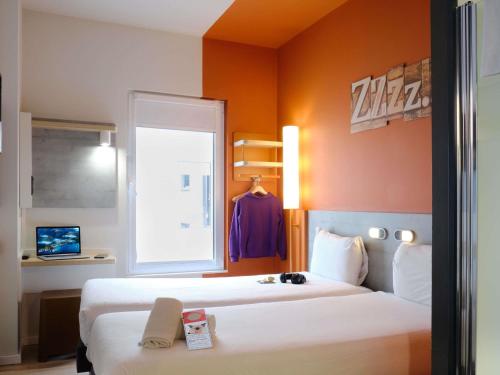 a hotel room with two beds and a window at Ibis Budget Bilbao City in Bilbao
