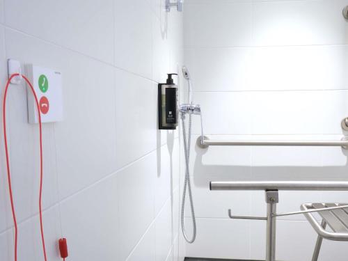 a white bathroom with a shower with a hose at Ibis Budget Bilbao City in Bilbao