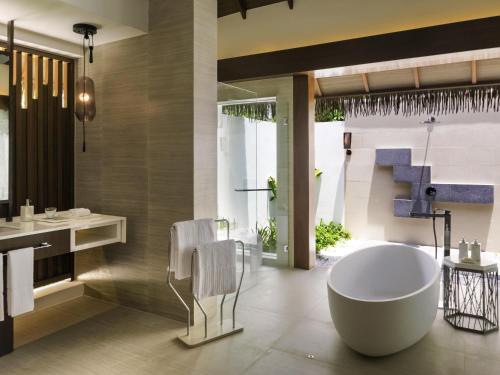 a bathroom with a tub and a sink at Pullman Maldives Maamutaa - All-Inclusive Resort - 50 percent off Transfers in Maamutaa
