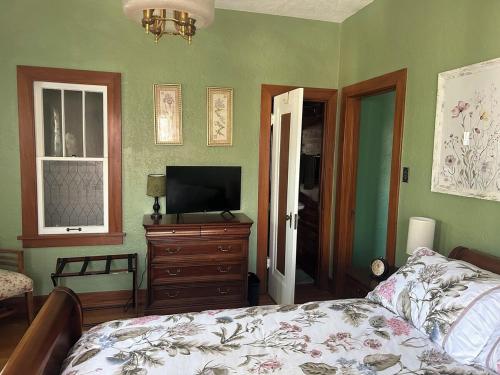 a bedroom with a bed and a television on a dresser at Private Gated Garden Suite in Historic Home, walk to UNM Football and Basketball, UNM and Pres Hospitals in Albuquerque