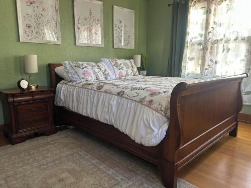 a bedroom with a bed with a wooden frame and a window at Private Gated Garden Suite in Historic Home, walk to UNM Football and Basketball, UNM and Pres Hospitals in Albuquerque
