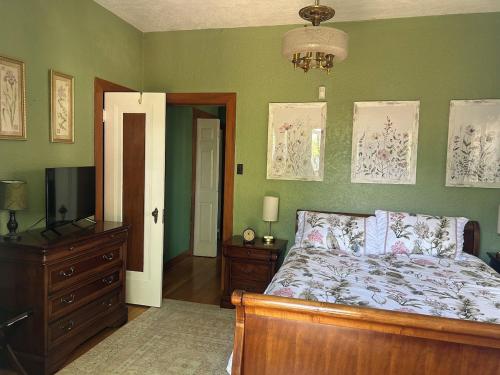 a bedroom with a bed and a dresser and a television at Private Gated Garden Suite in Historic Home, walk to UNM Football and Basketball, UNM and Pres Hospitals in Albuquerque