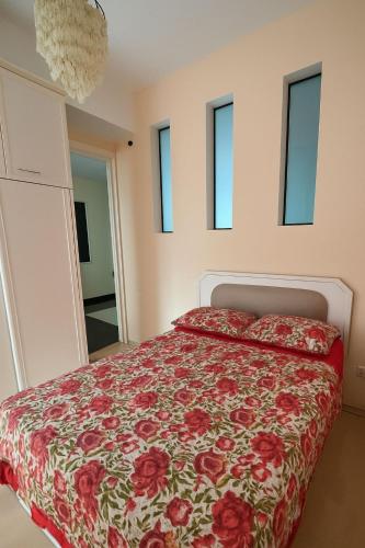 a bedroom with a bed with a red floral bedspread at apartament on vaja pshavela in Tbilisi City