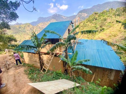 eine Person, die neben einem Gebäude mit blauen Dächern steht in der Unterkunft UNDE Village Camp Morogoro in Morogoro