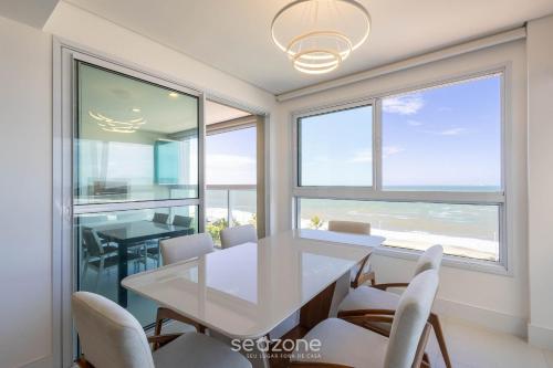 a dining room with a white table and chairs at Condomínio a beira-mar c/ piscina - SHC in Piçarras
