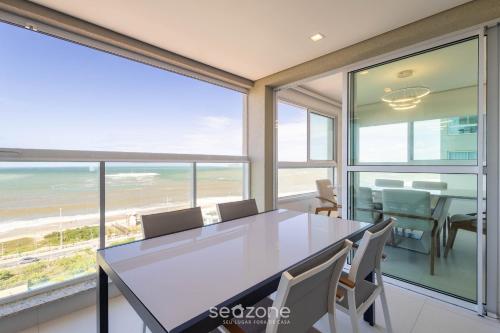 a dining room with a table and views of the ocean at Condomínio a beira-mar c/ piscina - SHC in Piçarras