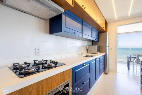 a kitchen with blue cabinets and a stove top oven at Condomínio a beira-mar c/ piscina - SHC in Piçarras