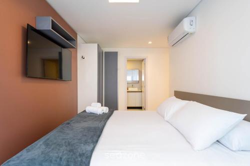 a bedroom with a bed and a tv on the wall at Condomínio a beira-mar c/ piscina - SHC in Piçarras
