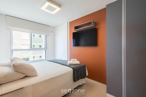 a bedroom with a bed and a tv on a wall at Condomínio a beira-mar c/ piscina - SHC in Piçarras